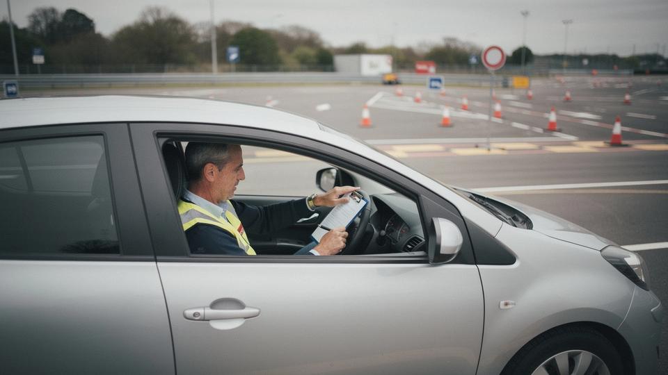Instructor coaching an experienced driver through a supervised hazard recognition drill on a closed course